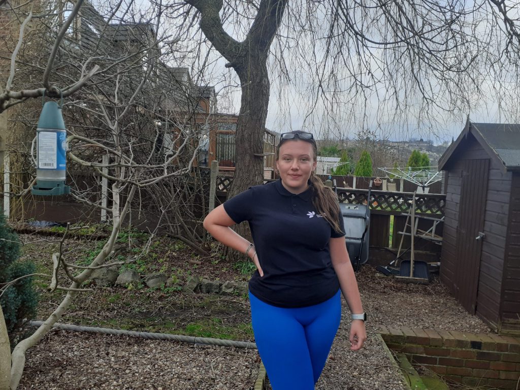 A women posing for a photo with her hand on her hip outside next to a tree