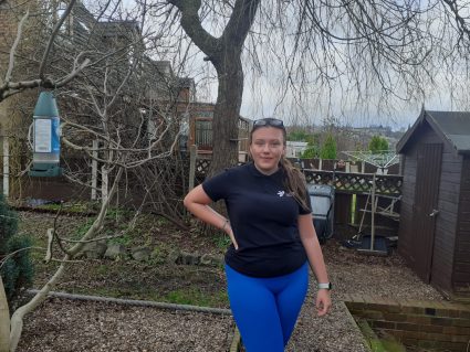A women posing for a photo with her hand on her hip outside next to a tree