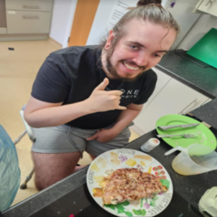 A man posing for the camera, with a plate of pizza