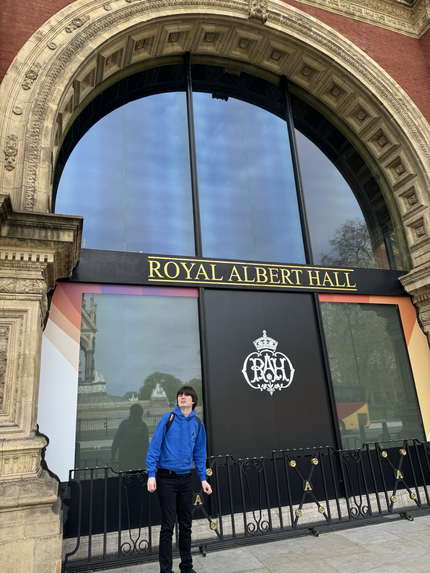 A boy stands outside doors of Royal Albert Hall