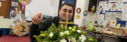 A man sat at a table decorating flowers in a church