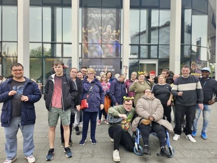 A group of people posing for a photo outside a theatre building