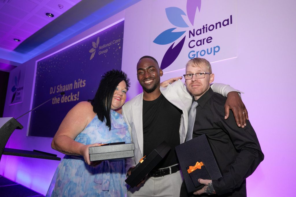 Three people standing with their awards, smiling
