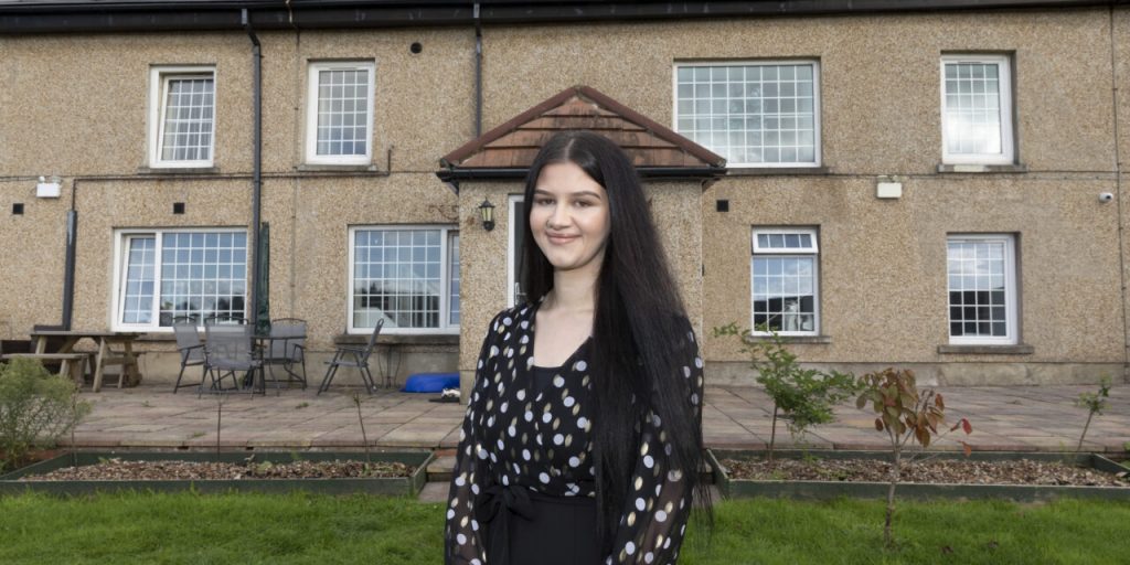 A lady standing outside in front of a house