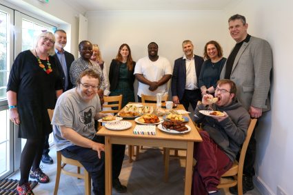 A group of people sat and standing around a table