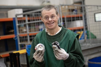 A man holding two crushed cans which he has recycled