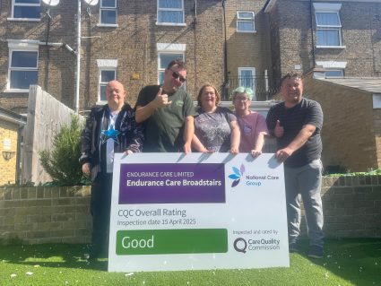 Five happy people holding a sign which says good