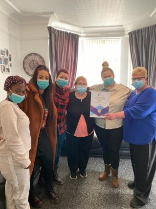 A group of people wearing face masks holding a certificate