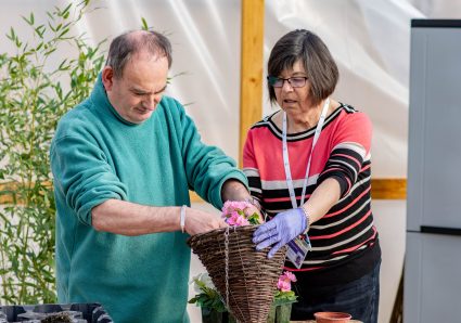 Two people planting seeds into a hanging basket