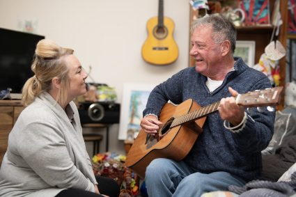 A man playing a guitar to a woman