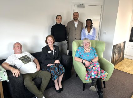 A group of people sat and stood in a living room setting