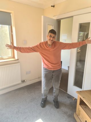 A man with his arms out wide stood in a living room