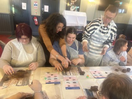 People taking part in clay modelling while learning about bowel cancer symptoms