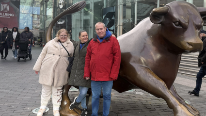 Three people stood in front of a statue of a bull