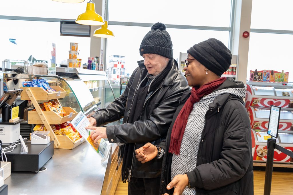 A man and woman stood at a cafe counter looking at a menu