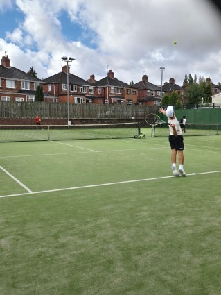 A tennis pitch with a person serving