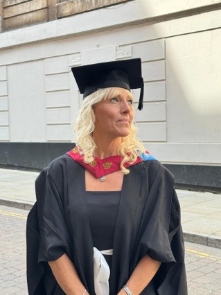 A blonde lady wearing a university graduation outfit