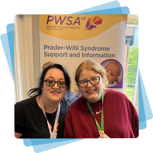 Two women stood in front of a banner with Prader-Willi Syndrome information and support written on it